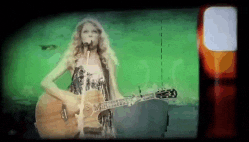 a woman is singing into a microphone while holding a guitar