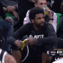 a man in a nets shirt sits in the stands