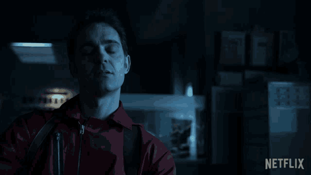 a man in a red jumpsuit is standing in a dark room with a netflix logo on the bottom right
