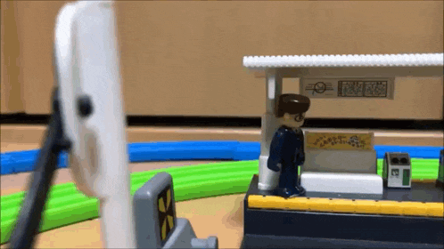 a toy train station with a man standing in front of it .