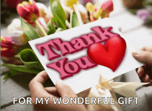a person holding a thank you card in front of flowers