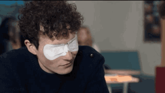 a man with a bandage on his eye looks at the camera