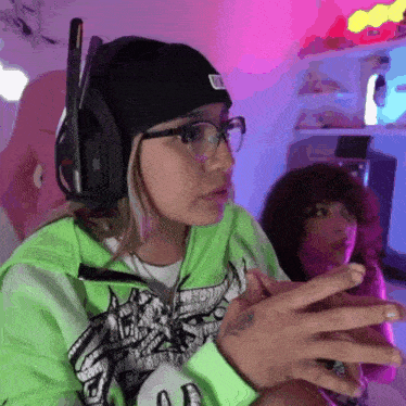 a woman wearing headphones and a green hoodie has a tattoo on her hand