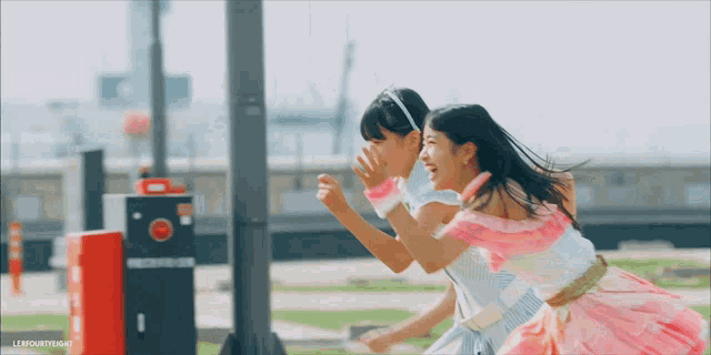 two girls are running in front of a red box that says lifefourteenlight