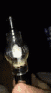 a person is holding a glass bottle with a light inside of it in their hand .
