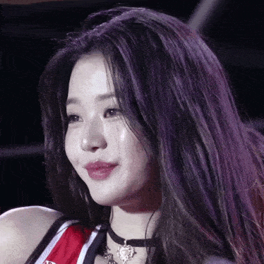 a woman with purple hair is wearing a choker and a red and white jersey