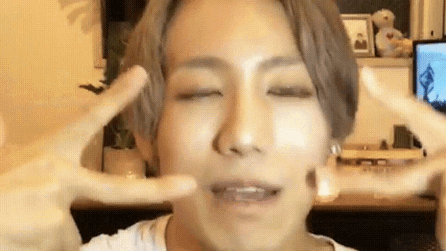 a close up of a person making a funny face with their hands