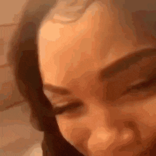 a close up of a woman 's face with her eyes closed and a blurred background .