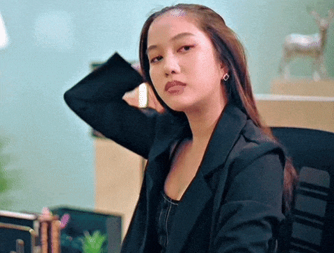 a woman wearing a black jacket and earrings is sitting in an office chair .