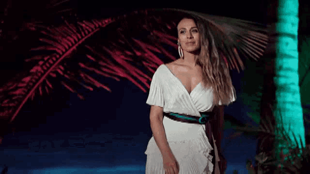 a woman in a white dress is standing in front of a palm tree and the words hay mas imagenes para ti