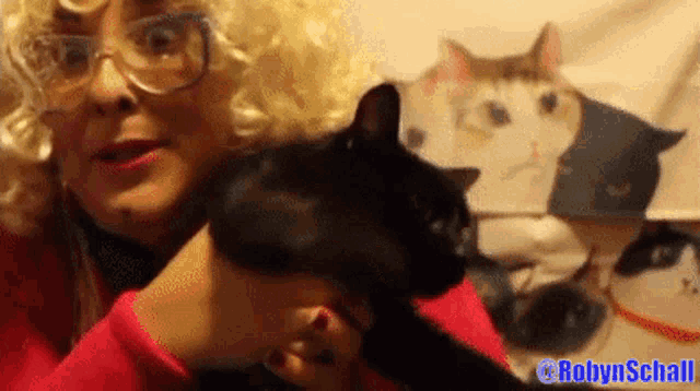 a woman in a blonde wig holds a black cat with the name robynschall on the bottom right