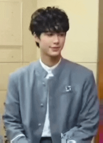 a young man wearing a gray jacket and a white shirt is smiling .