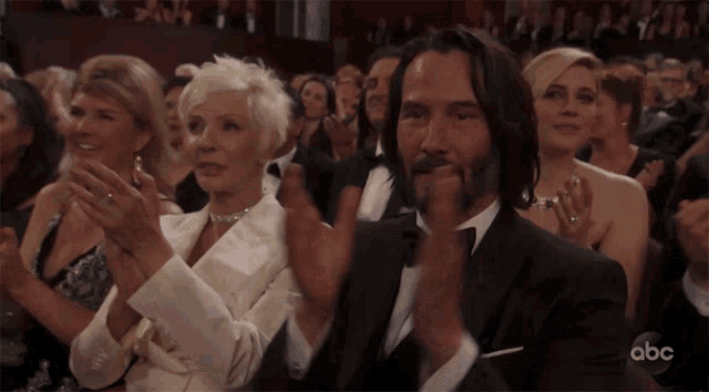 a man in a tuxedo is applauding while sitting in a crowd with abc written on the bottom