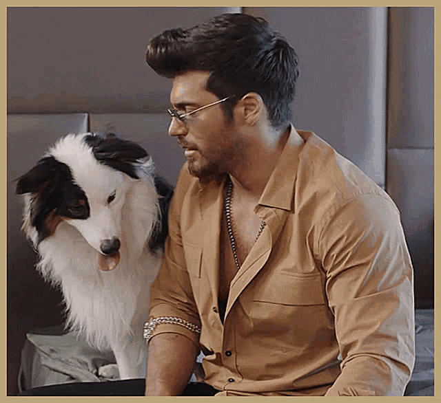 a man wearing glasses is sitting next to a dog