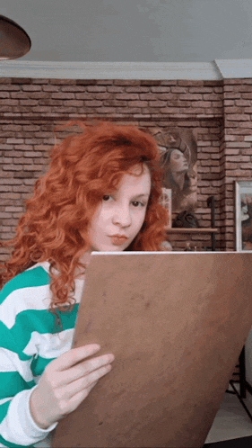 a woman with red hair is holding a piece of paper