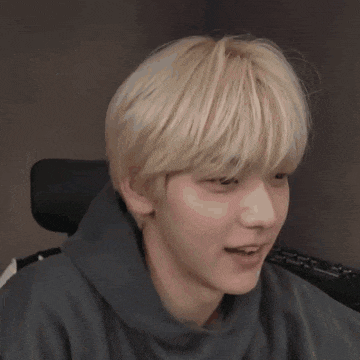 a close up of a person 's face with blonde hair and a black hoodie .