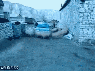 a blue car is driving down a dirt road with the words welele.es written on the bottom