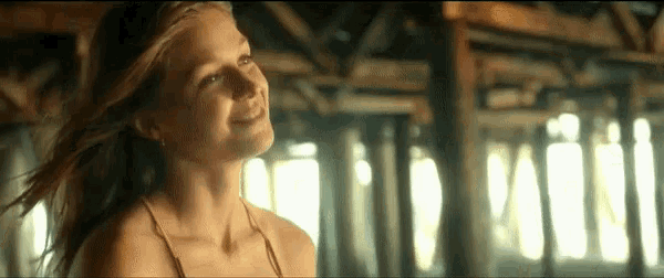 a woman in a bikini is smiling and looking up in a room .
