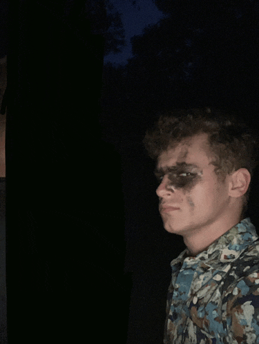 a man with black paint on his face is wearing a blue shirt