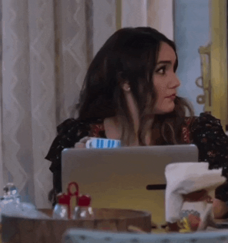 a woman is sitting at a table with a laptop computer and a cup of coffee .
