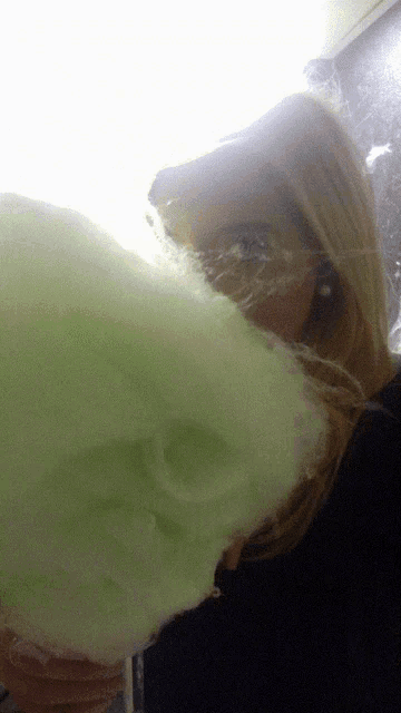 a woman eating green cotton candy with her mouth