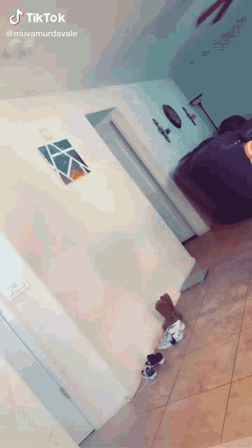 a tiktok video of a hallway with a painting on the wall and shoes on the floor