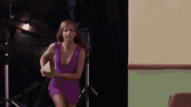 a woman in a purple dress is running through a room holding a book .