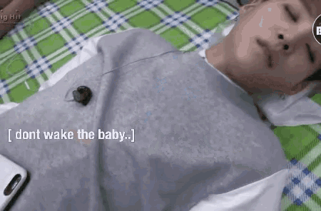 a man is laying on a bed with a cell phone and headphones on his neck .