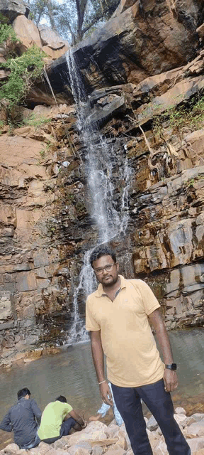 a man is standing in front of a waterfall