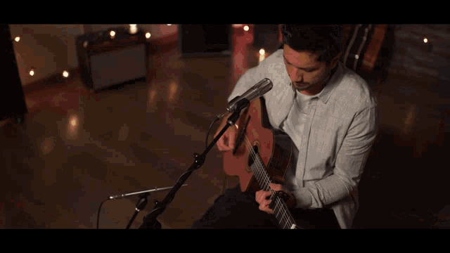 a man singing into a microphone while holding a guitar