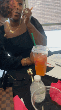 a woman sitting at a table with a drink in a starbucks cup