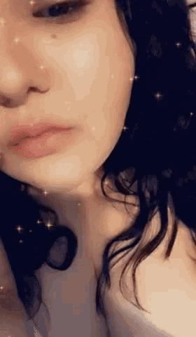 a close up of a woman 's face with sparkles in the background