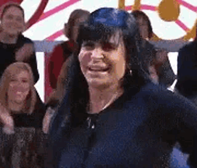 a woman is standing in front of a crowd of people and smiling at the camera .