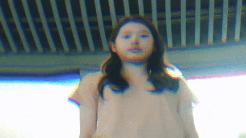 a woman in a pink shirt is standing in front of a window