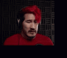 a man wearing headphones and a red shirt is making a funny face .