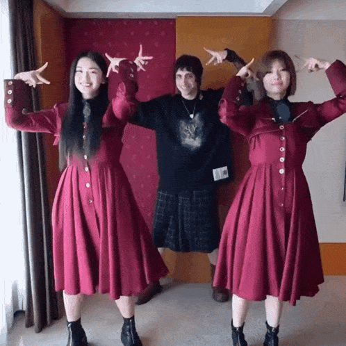 a man in a kilt and two women in red dresses are posing for a picture