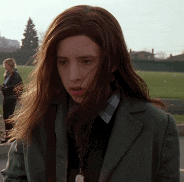 a woman with long hair is wearing a green coat