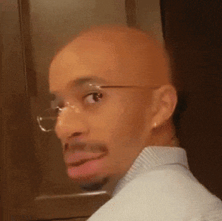 a bald man wearing glasses is making a funny face with his mouth open