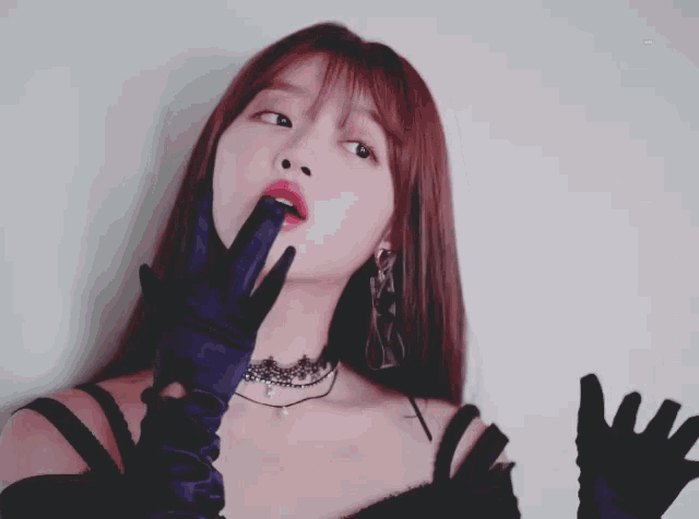 a woman wearing black gloves and a choker looks up
