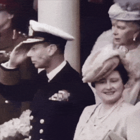 a man in a navy uniform salutes a woman in a hat