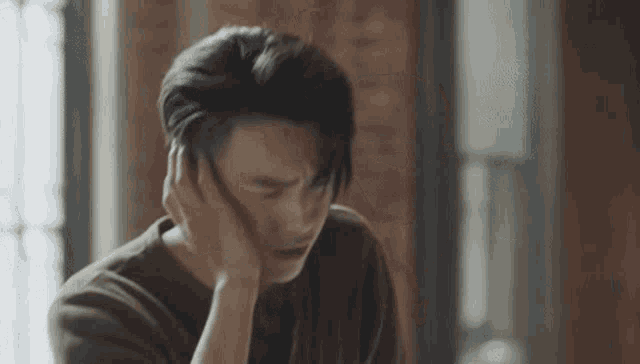 a man is sitting at a table with his hand on his ear .