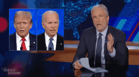 a man in a suit and tie stands in front of a screen that says daily show