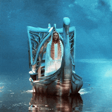 a woman in a white dress sits on a swan boat in the water
