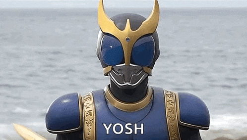 a man in a superhero costume is standing on a beach with a sword in his hand .