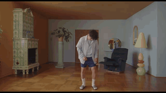 a man is dancing in a living room with a chair and a fireplace