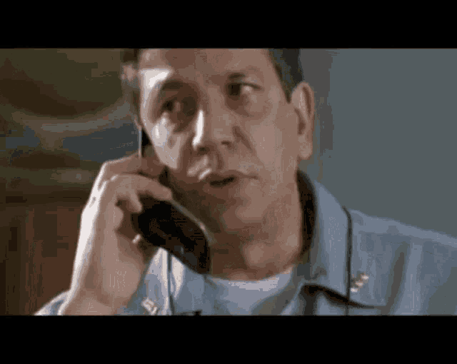 a man in a blue shirt is talking on a phone