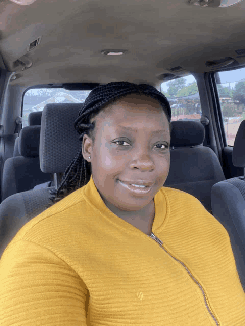 a woman in a yellow sweater is sitting in a car