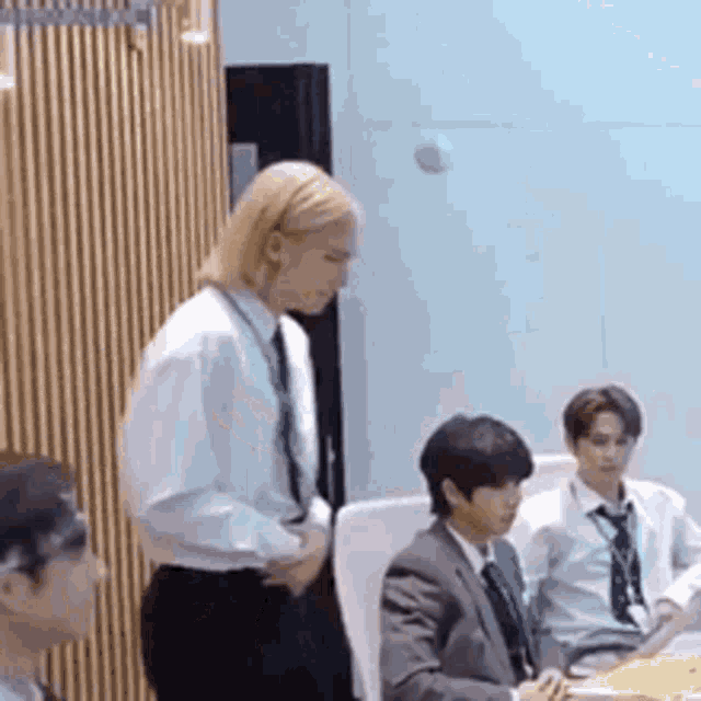 a group of men in suits and ties are sitting at a table in a room .
