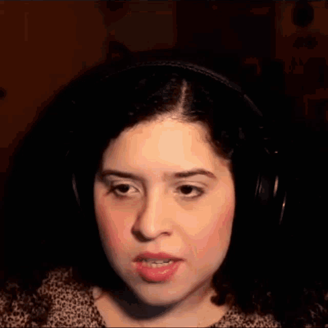 a woman wearing headphones smiles and looks at the camera