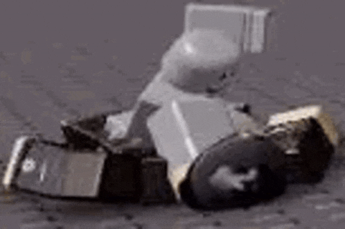 a lego man is sitting in a wheelchair on the ground with his legs crossed .